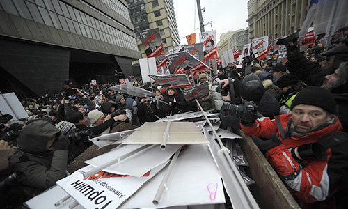 Полицейские требуют граждан освободить проезжую часть. Тем временем, некоторые из оставшихся фотографируются на фоне мусорных баков, в которых сложены портреты депутатов. Полицейские наблюдают за этим с огнетушителями наготове.