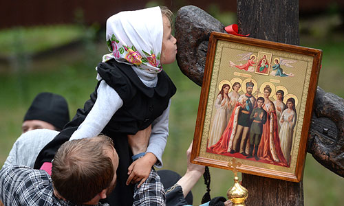 Ребенок целует поклонный крест на Ганиной Яме, где были похоронены останки в Екатеринбурге.