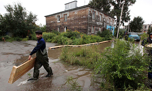 Рабочие строят деревянные мостки к домам, подтопленным паводковыми водами. Уровень воды в реке Амур у Хабаровска в воскресенье достиг исторического максимума в 642 сантиметра.