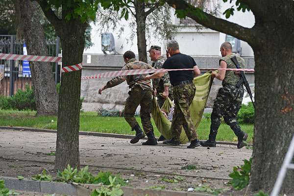 Народные ополченцы несут тело погибшего в результате авиаатаки на здание обладминистрации в Луганске.