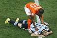 Голландский игрок Вейналдум склонился над травмированным аргентинцем Маскерано.