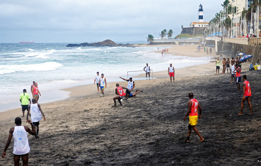 Игроки сражаются за мяч на пляже портового города Сальвадор в Бразилии