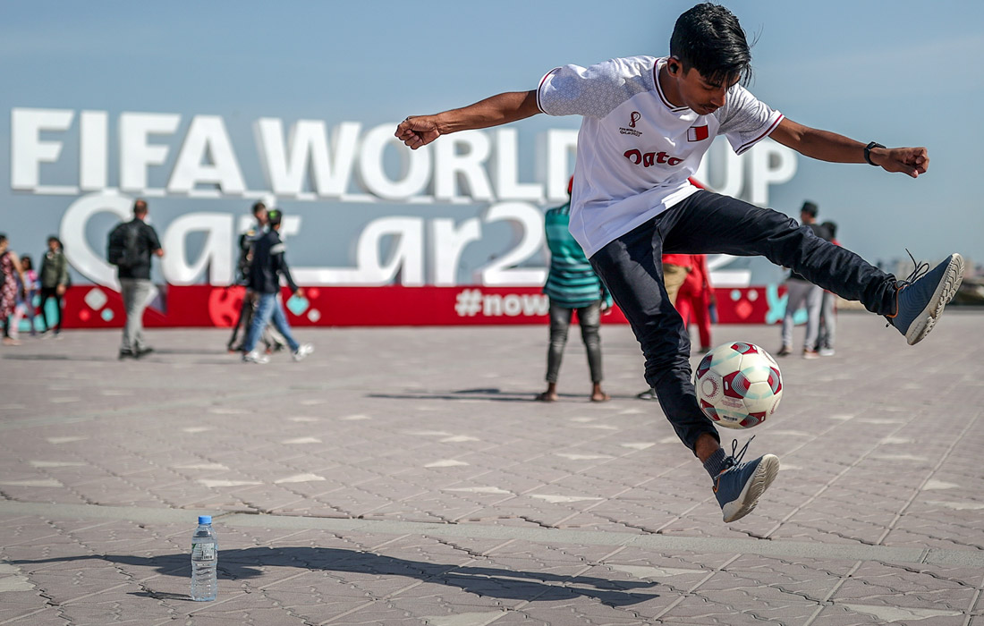 Люди у скульптуры, посвященной чемпионату миру по футболу-2022, на городской набережной