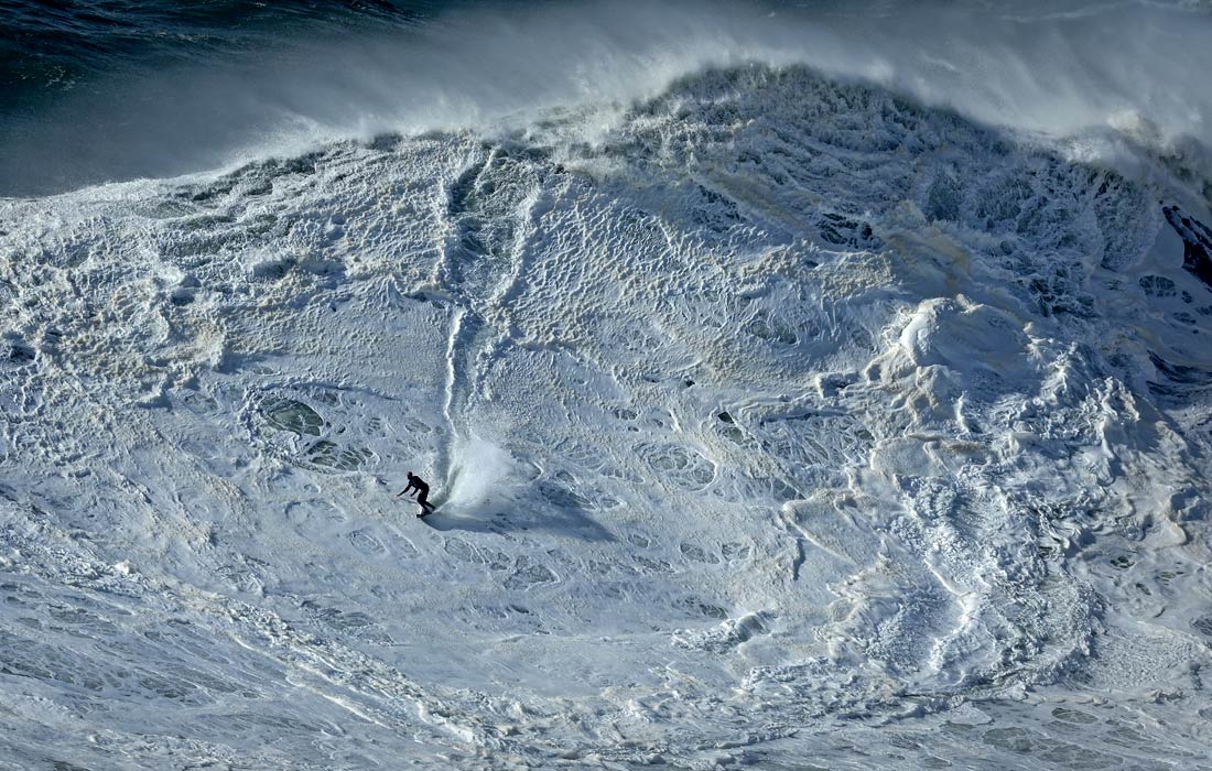 Серфинг во время сезона больших волн в португальском Назаре