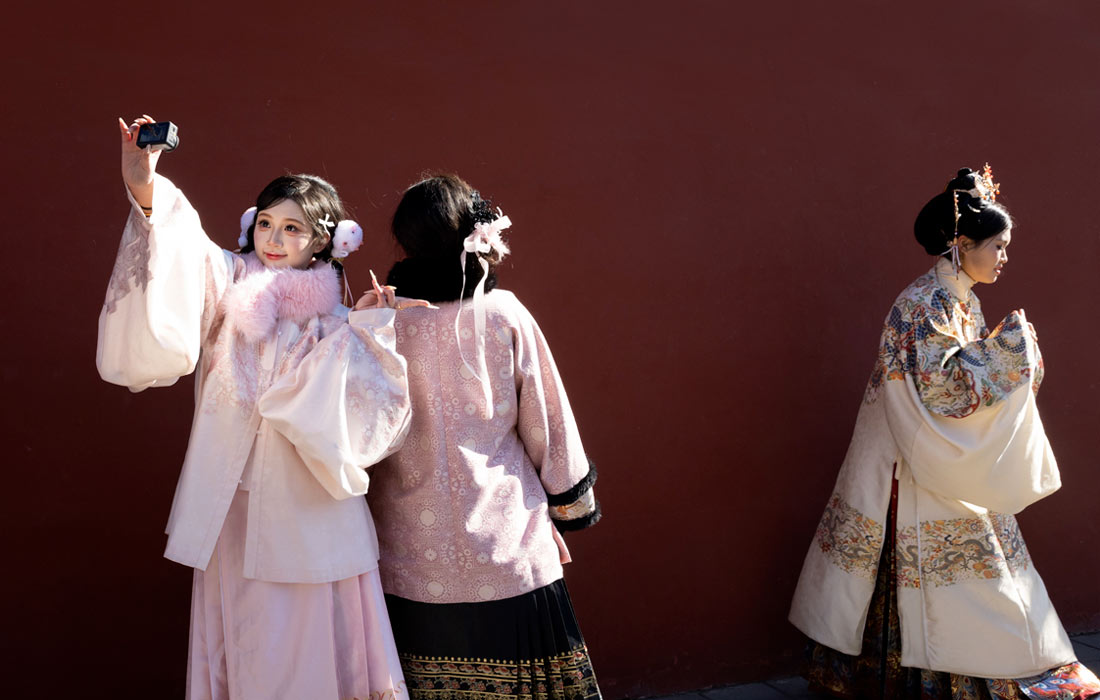 Девушки в национальных костюмах фотографируются возле Запретного города в Пекине